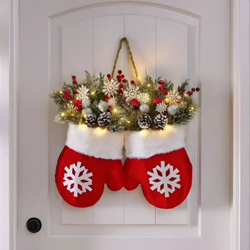Red christmas mittens glove shaped wreath filled with festive greenery, red berries, pinecones, and twinkling lights for christmas garland creative decor