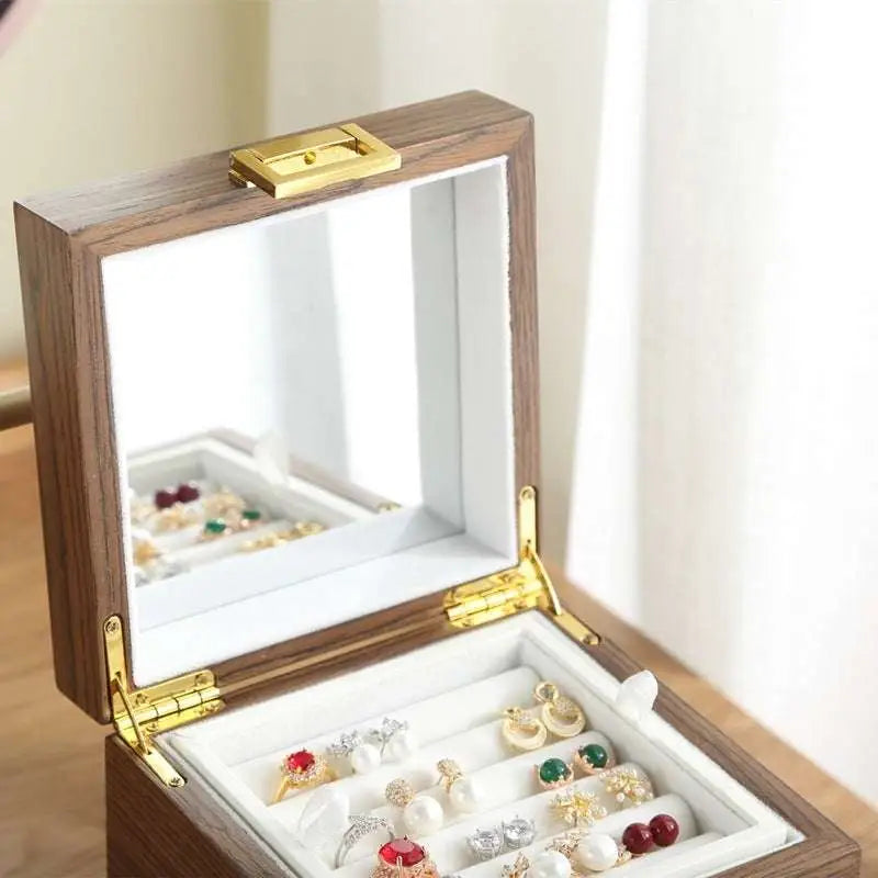 Classical wooden jewelry box with gold-tone latch, interior mirror, and white velvet-lined compartments holding earrings