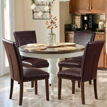 Round dining table with dark wood top and white pedestal base surrounded by colamy upholstered parsons dining chairs set of 4
