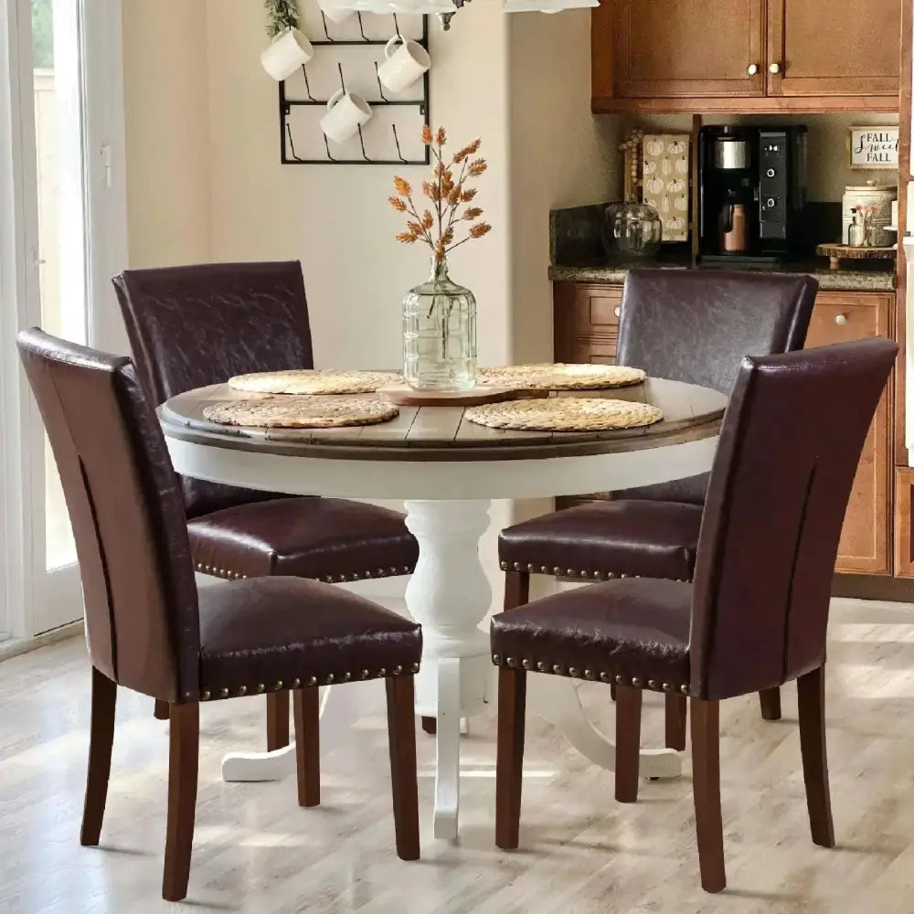 Round dining table with dark wood top and white pedestal base surrounded by colamy upholstered parsons dining chairs set of 4