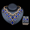 A colorful exaggerated bride necklace and earring set featuring a royal blue teardrop pendant with gold-tone rhinestones