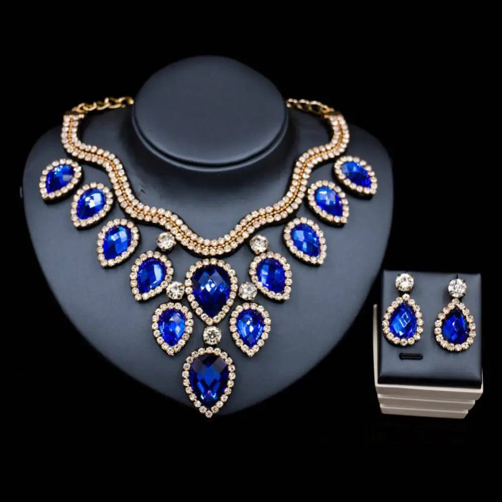 A colorful exaggerated bride necklace and earring set featuring a royal blue teardrop pendant with gold-tone rhinestones