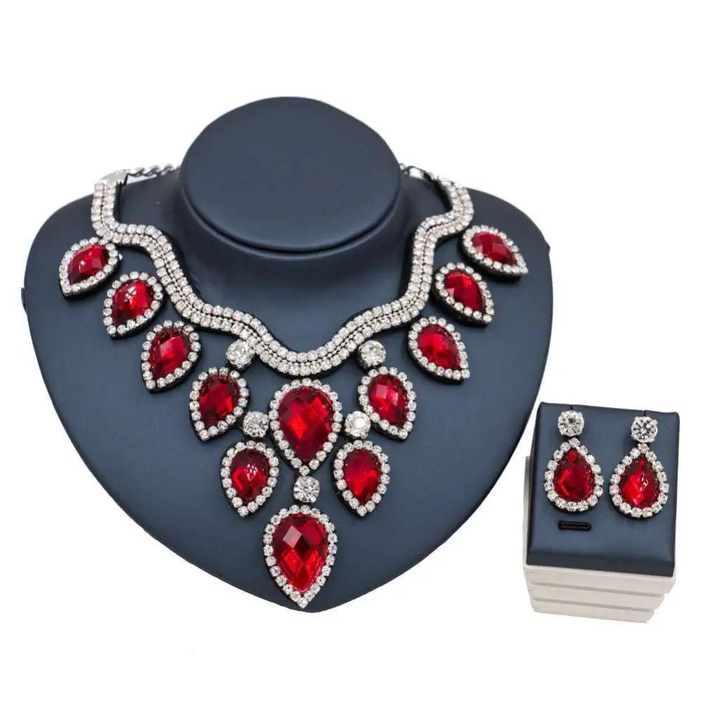 Colorful exaggerated bride necklace and earring set with red teardrop crystals and silver metal on dark blue bust
