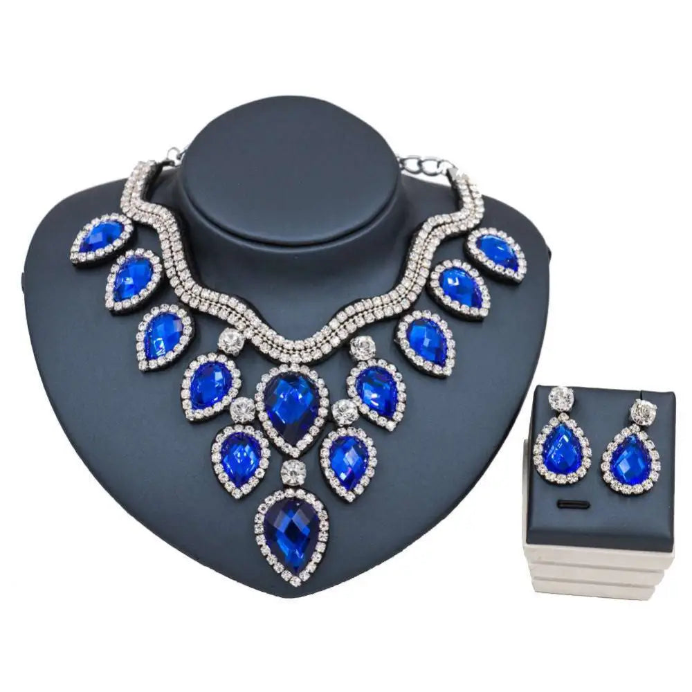 A dazzling royal blue colorful exaggerated bride necklace and earring set with clear crystals and silver metalwork displayed on black bust