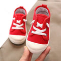 Red canvas toddler sneakers with white laces and rubber soles designed as colorful kindergarten indoor shoes