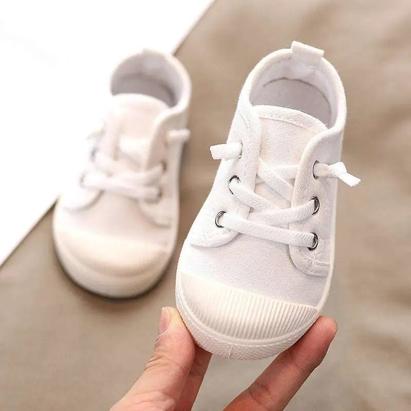 White canvas toddler sneaker with matching laces and ribbed rubber soles designed for colorful kindergarten indoor shoes