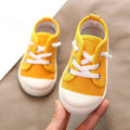 Bright yellow colorful kindergarten indoor shoes with white laces and rubber soles designed for indoor use