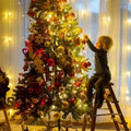 A lush green christmas tree decorated with colorful led snowflake lights red and gold ornaments and festive decorations