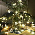String of colorful led snowflake lights with warm white bulbs wrapped around a clear glass vase