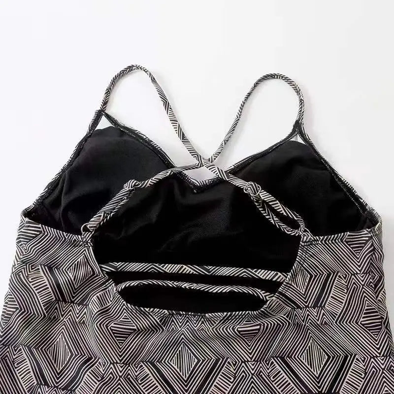 Black and white color split geometric one-piece swimsuit with crisscross shoulder straps in conservative artistic color style