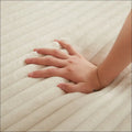 A hand rests on a cream corduroy round recliner neck pillow design with soft ribbed texture and plush material