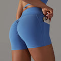 Blue high-waisted athletic shorts with ruched side seam and front pocket design fitness holding a smartphone