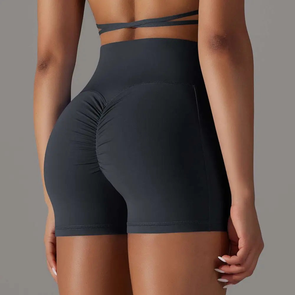 High-waisted athletic shorts in dark gray with ruched back detail featuring pocket design fitness use