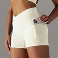 Cream high waisted athletic shorts with a pocket design fitness feature holding a smartphone for active use