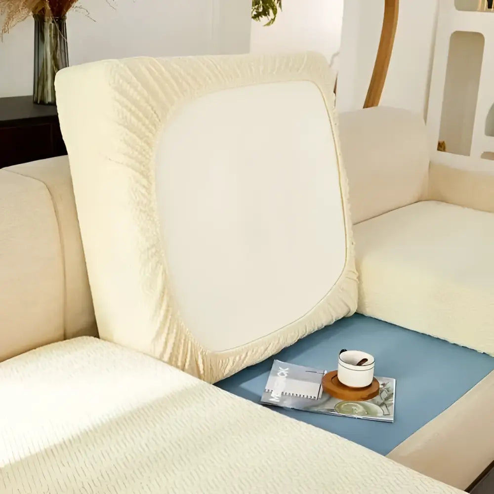 Back view of cream stretchy universal sofa cover made of textured fabric with elasticized edges for sofa cushions