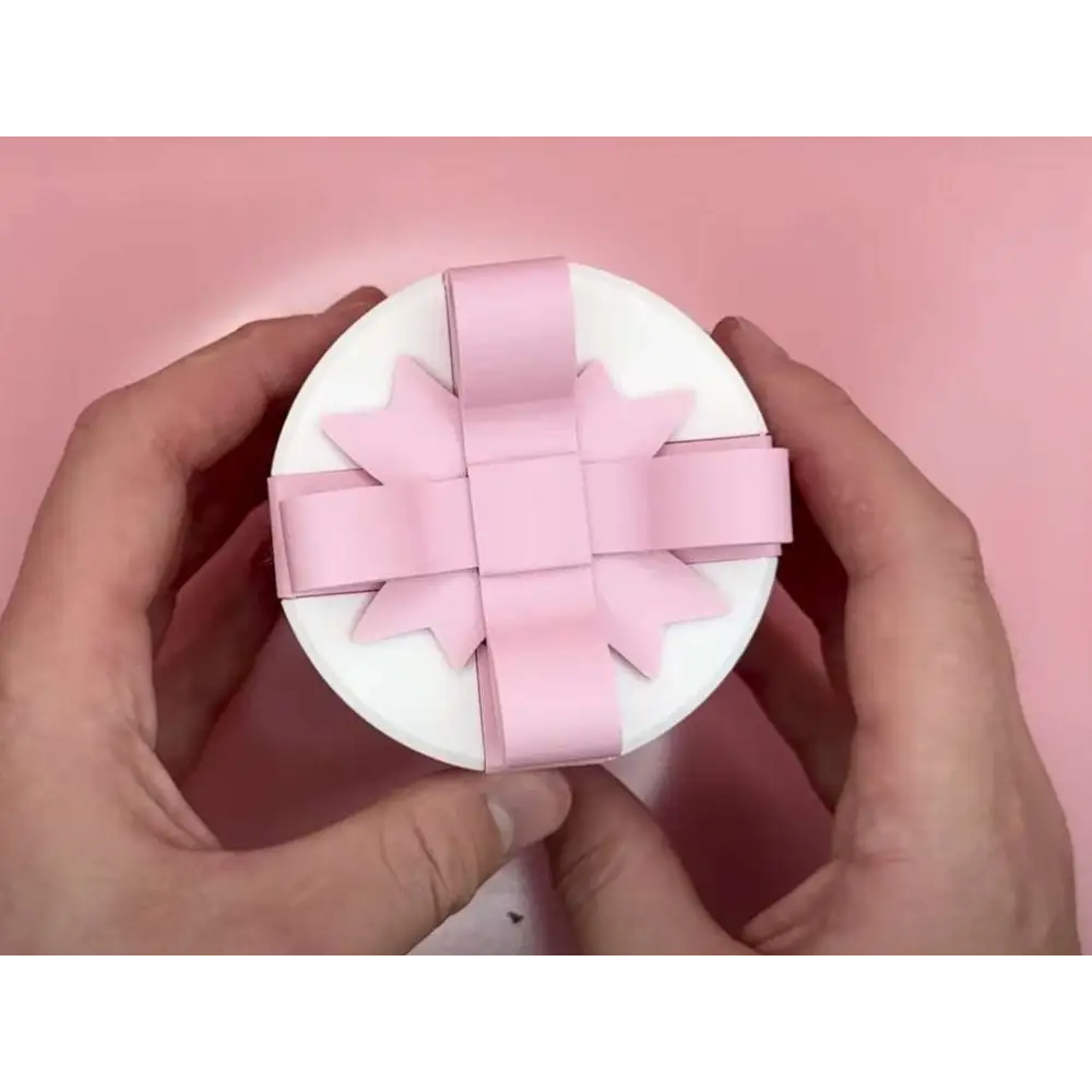 A white circular valentine day gift box with a delicate creative bowknot pink ribbon bow on top