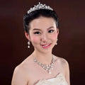 A sparkling silver tiara with intricate crystal details in a crystal flower necklace and bridal headdress set