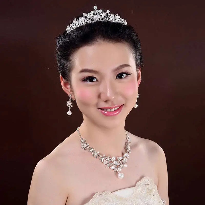A sparkling silver tiara with intricate crystal details in a crystal flower necklace and bridal headdress set