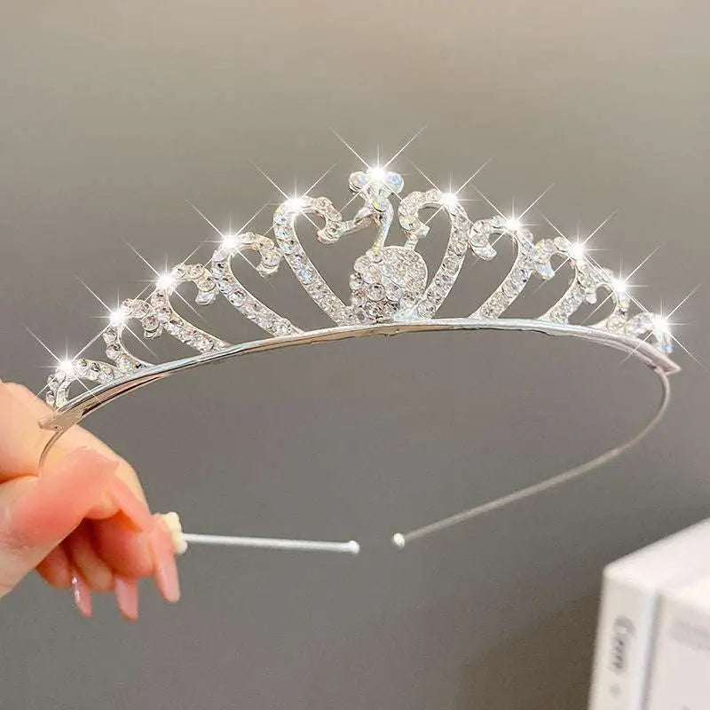 A sparkling silver crystal pearl girls princess crown headdress with heart-shaped crystals and a central peacock motif