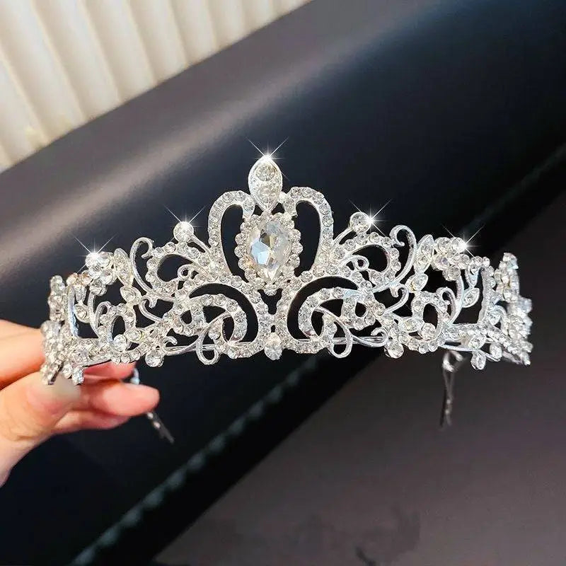 A sparkling silver crystal pearl girls princess crown headdress with floral patterns and a teardrop gemstone centerpiece