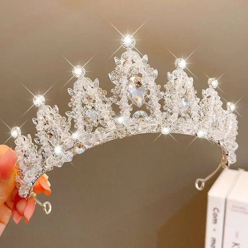 A sparkling silver crystal pearl girls princess crown headdress with intricate crystal embellishments and teardrop gemstone