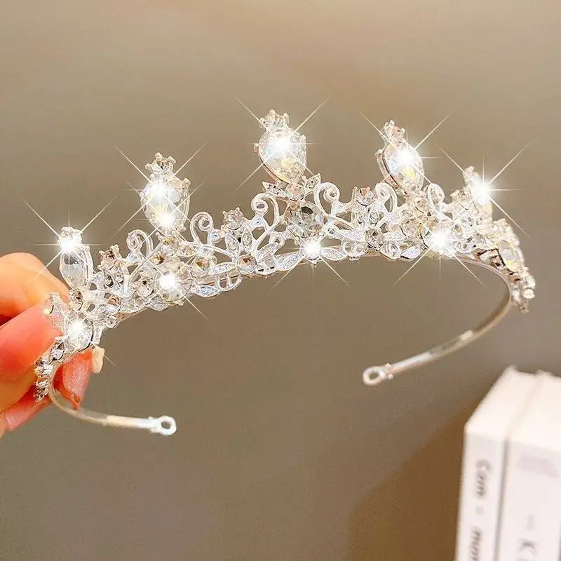 A sparkling silver crystal pearl girls princess crown headdress with intricate filigree and clear faceted crystals