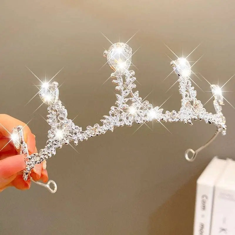 A sparkling silver crystal pearl girls princess crown headdress with intricate leaf floral patterns and pear-shaped crystals