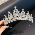 A sparkling silver crystal pearl girls princess crown headdress with intricate leaf and floral patterns and teardrop crystals