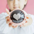 Pink circular led digital electronic cute alarm clock displaying a pixelated white heart on its dark screen