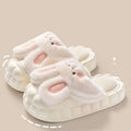 Soft white plush bunny slippers with pink inner ears and embroidered black eyes, featuring a cushioned sole.