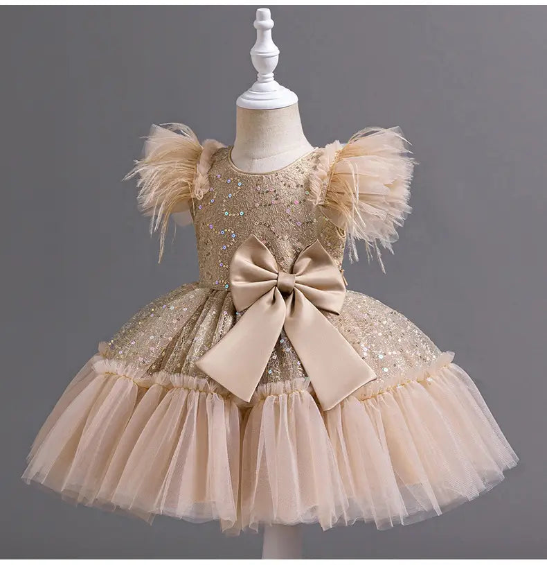 a shimmering gold sequined toddler wedding dress tulle with fluffy feathered sleeves a large beige satin bow at the waist and a layered tulle skirt summer design