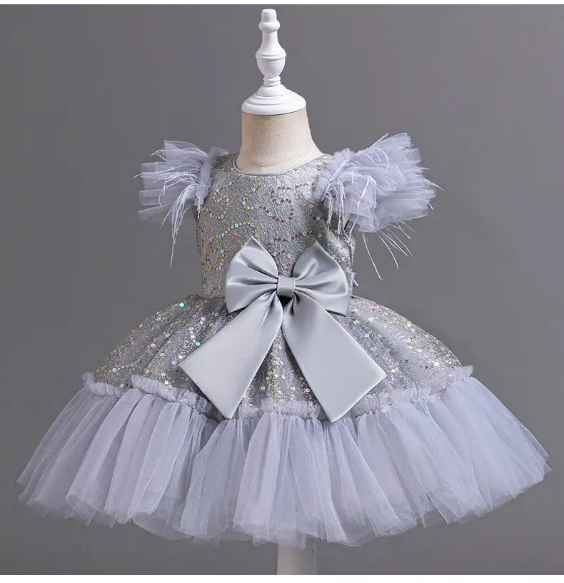 Silver sequined toddler wedding dress with feathered shoulder accents and a large satin bow at the waist layered in a dress tulle skirt ideal for a tulle skirt summer occasion.