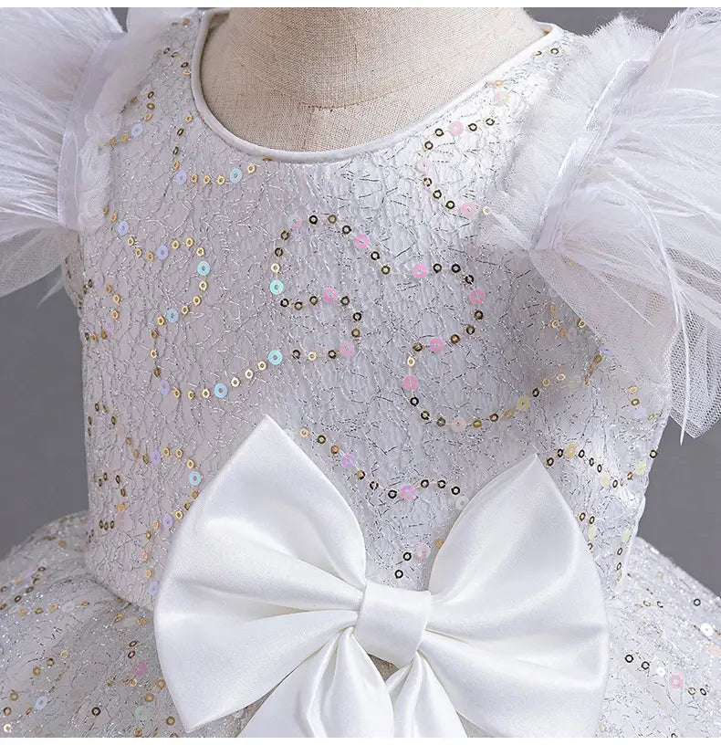 A delicate white wedding dress tulle skirt summer featuring shimmering sequins in pastel hues, voluminous tulle sleeves, and a prominent satin bow at the waist.