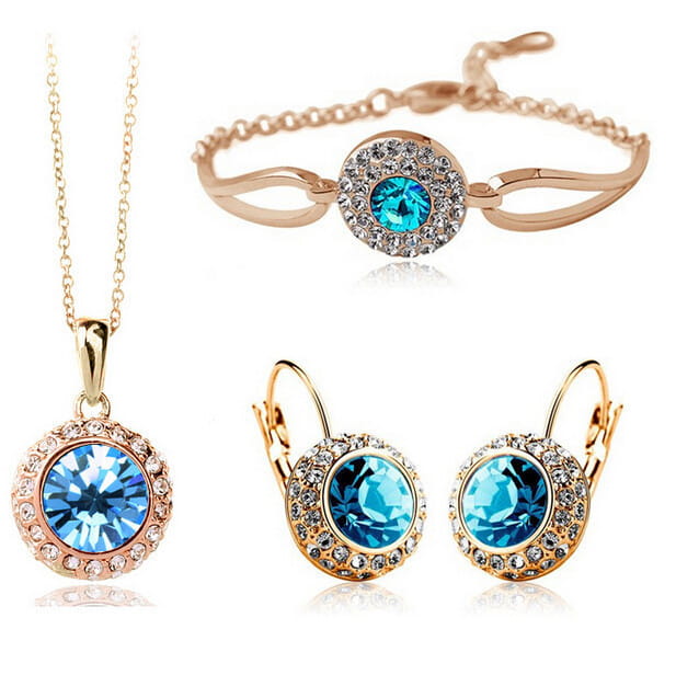 Elegant korean style jewelry set in rose gold tone featuring a central blue crystal and smaller clear crystals on silver pieces with fruit green accents.