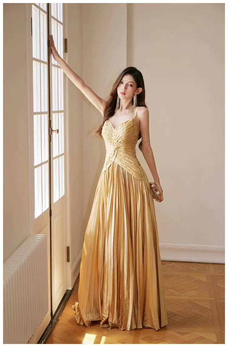 A shimmering gold satin heavy industry birthday dress featuring a pleated evening gown design with a fitted bodice and flowing skirt.