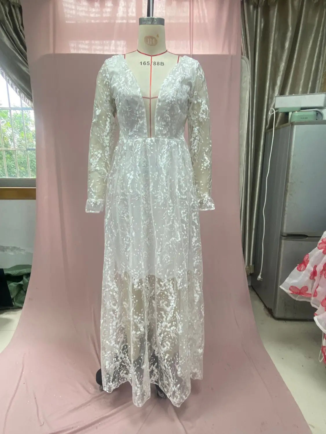A delicate white long sleeve wedding dress lace gown with a v-neckline and tiered skirt displayed on a mannequin.
