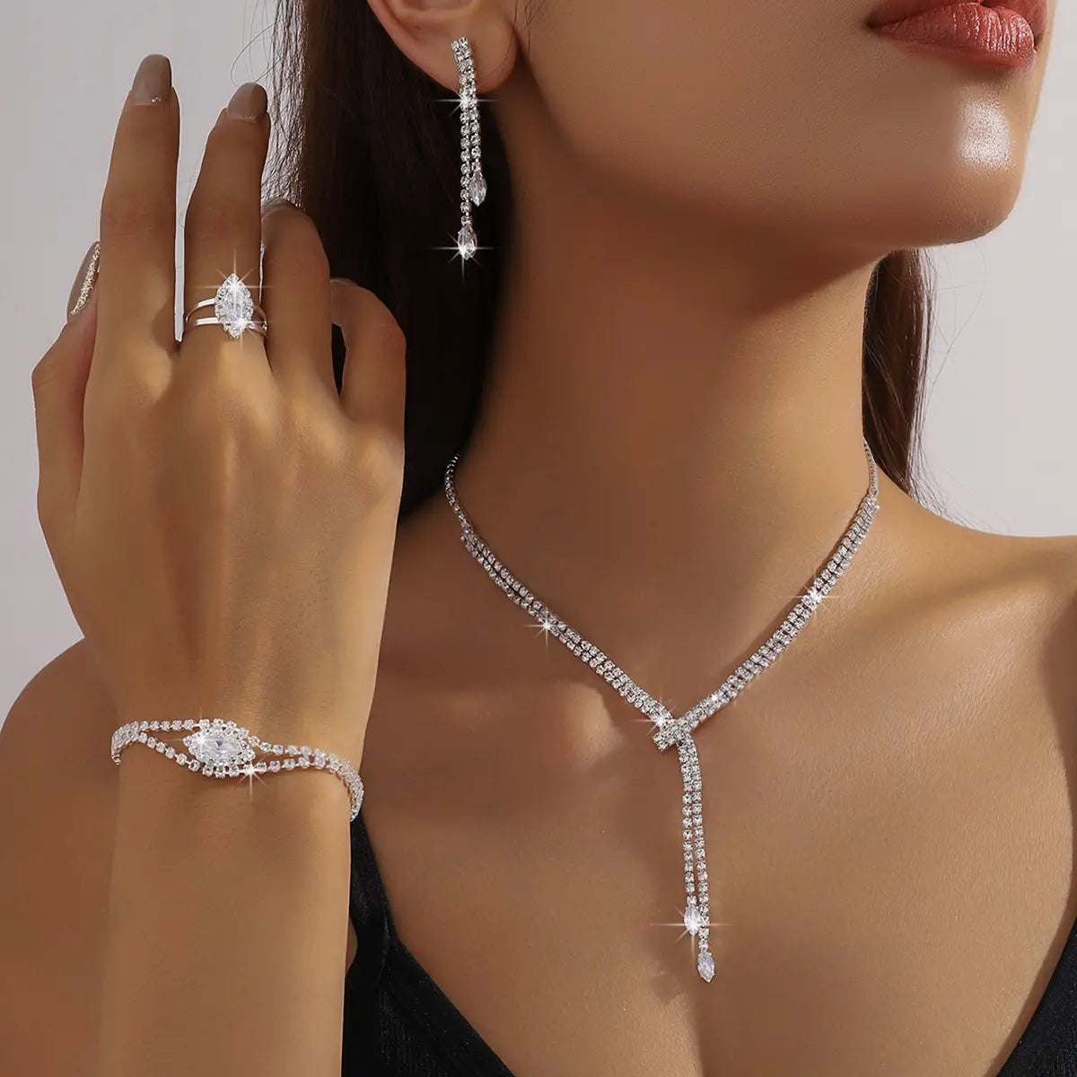 A sparkling diamond fashion simple necklace with a v-shaped design and dangling teardrop crystals in a necklace earring bracelet set.