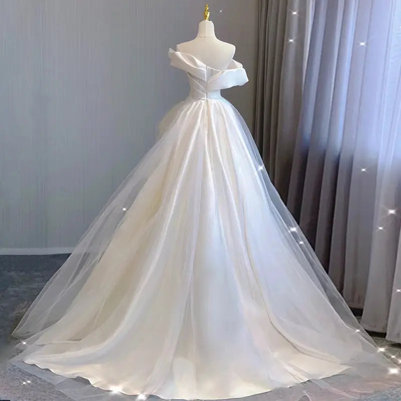 a flowing white off-the-shoulder wedding gown with a satin bodice and layered tulle skirt in temperament princess style french satin material