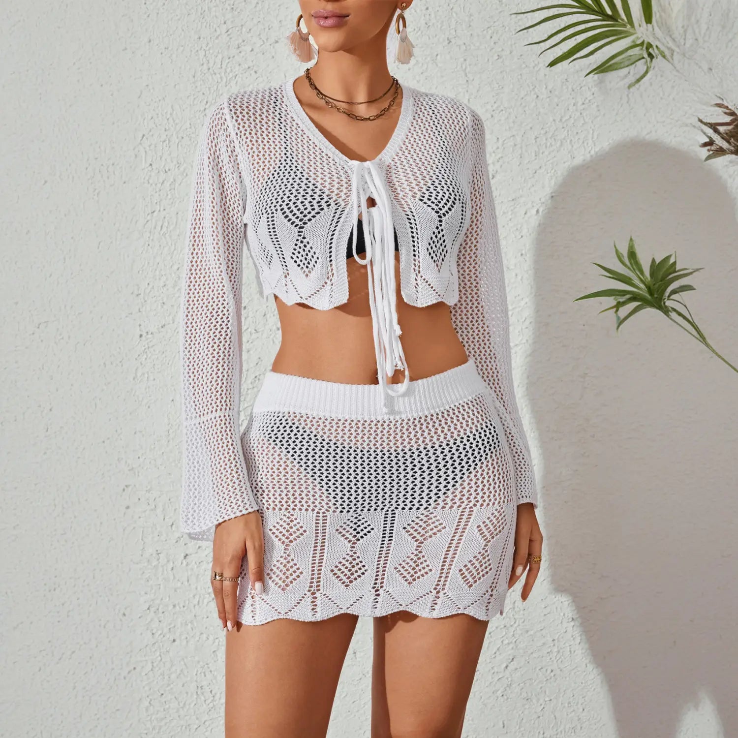 white crochet knitted beach bikini set with a cropped top featuring bell sleeves and a mini skirt with an intricate diamond patterned mesh design