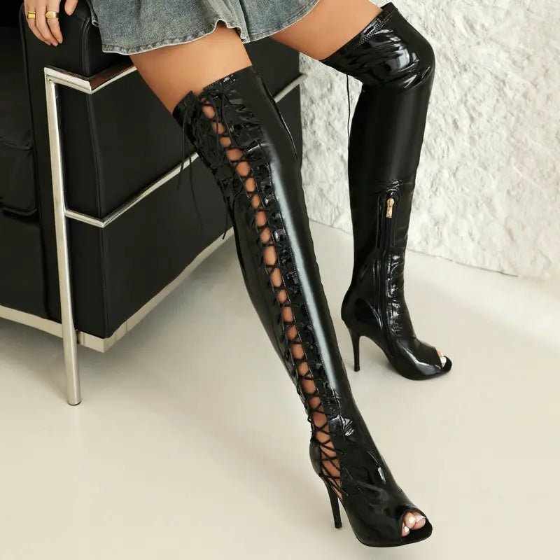 black patent leather female over the knee boots with lace up detailing, peep toe design, and medium heel height.