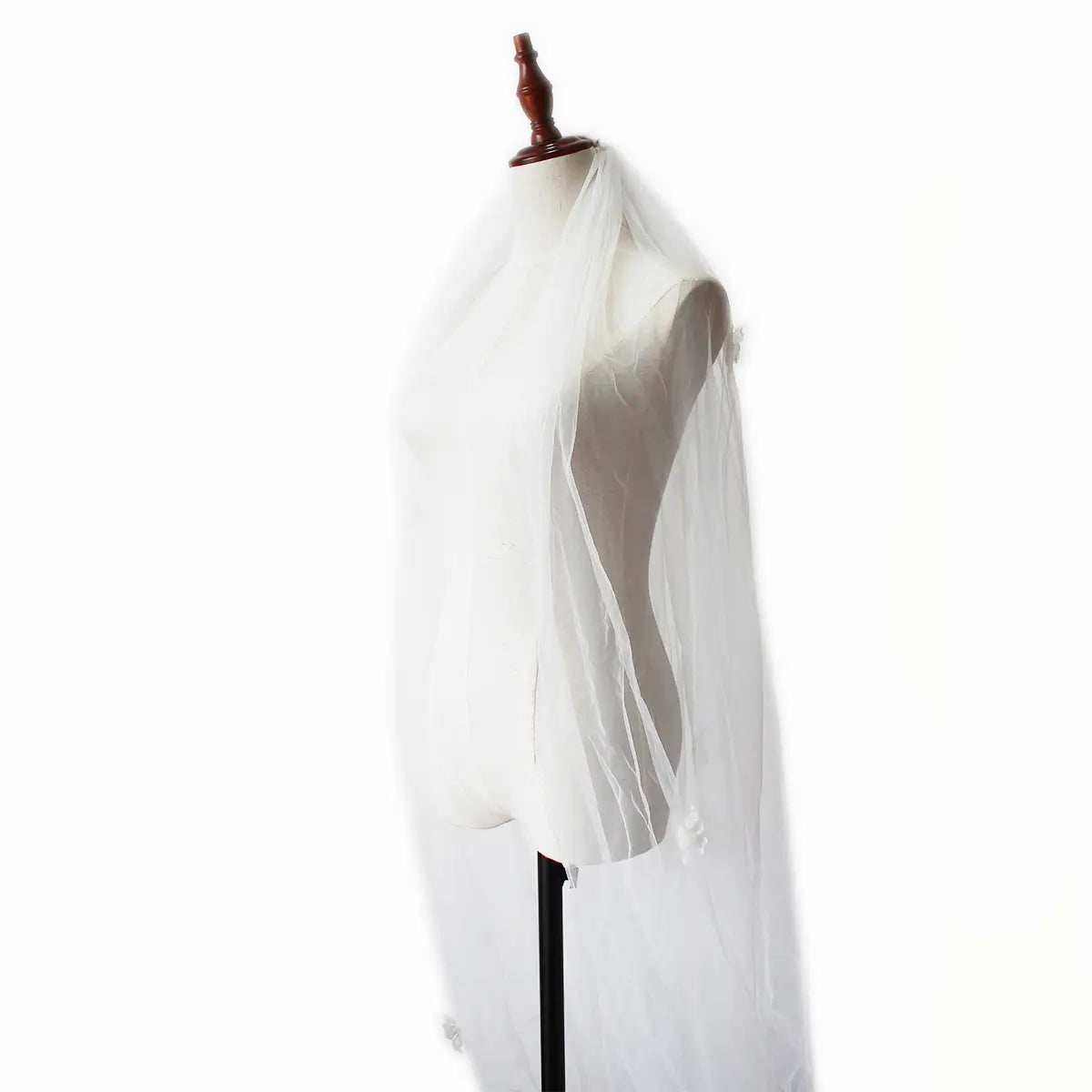 a delicate ivory lace bridal church wedding veil made of sheer white tulle with subtle folds and gentle transparency, draped over a mannequin as part of the wedding pearl long tail gown collection.