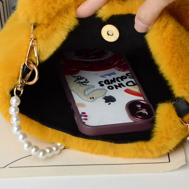 yellow fuzzy phone case with gold-toned hardware and a pearl chain design complements the yellow checkerboard plush bucket bag