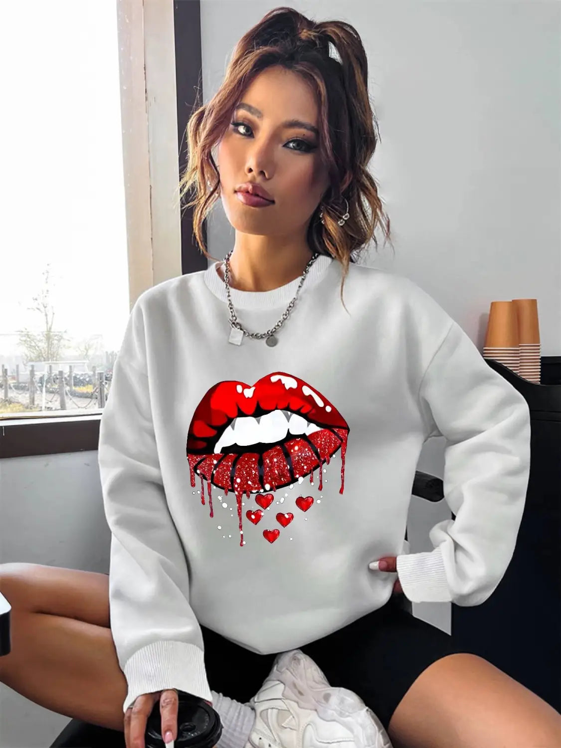 White glitter lips pocketed long sleeve sweatshirt in white featuring a bold red glittery lips graphic with a dripping effect and small hearts below.