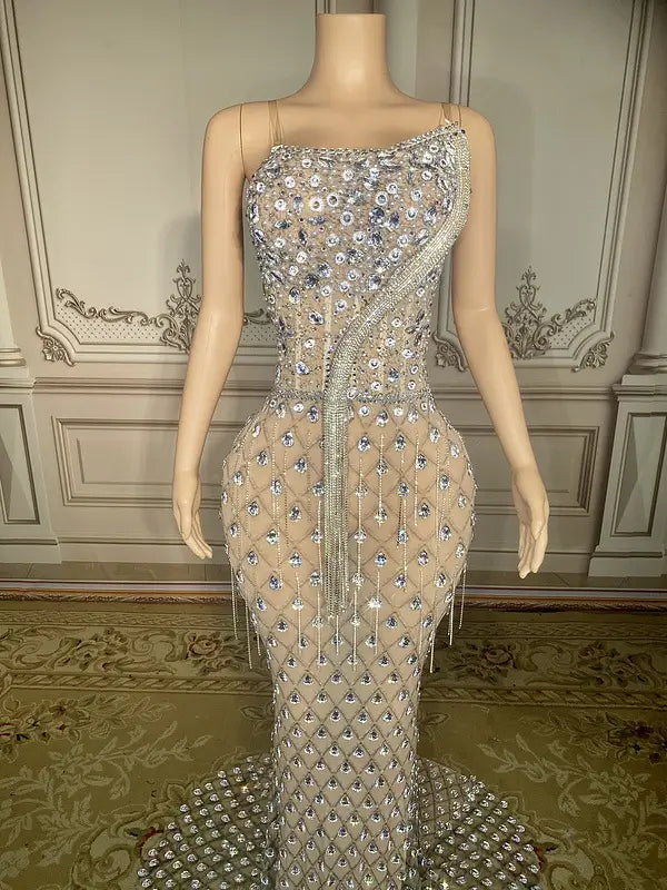 A shimmering silver beaded sexy elegant fishtail gown featuring a sheer fitted bodice and cascading fringe detailing.