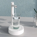 White minimalist smart desk dispenser electric water pouring clear liquid into glass for dark blue smart desk use
