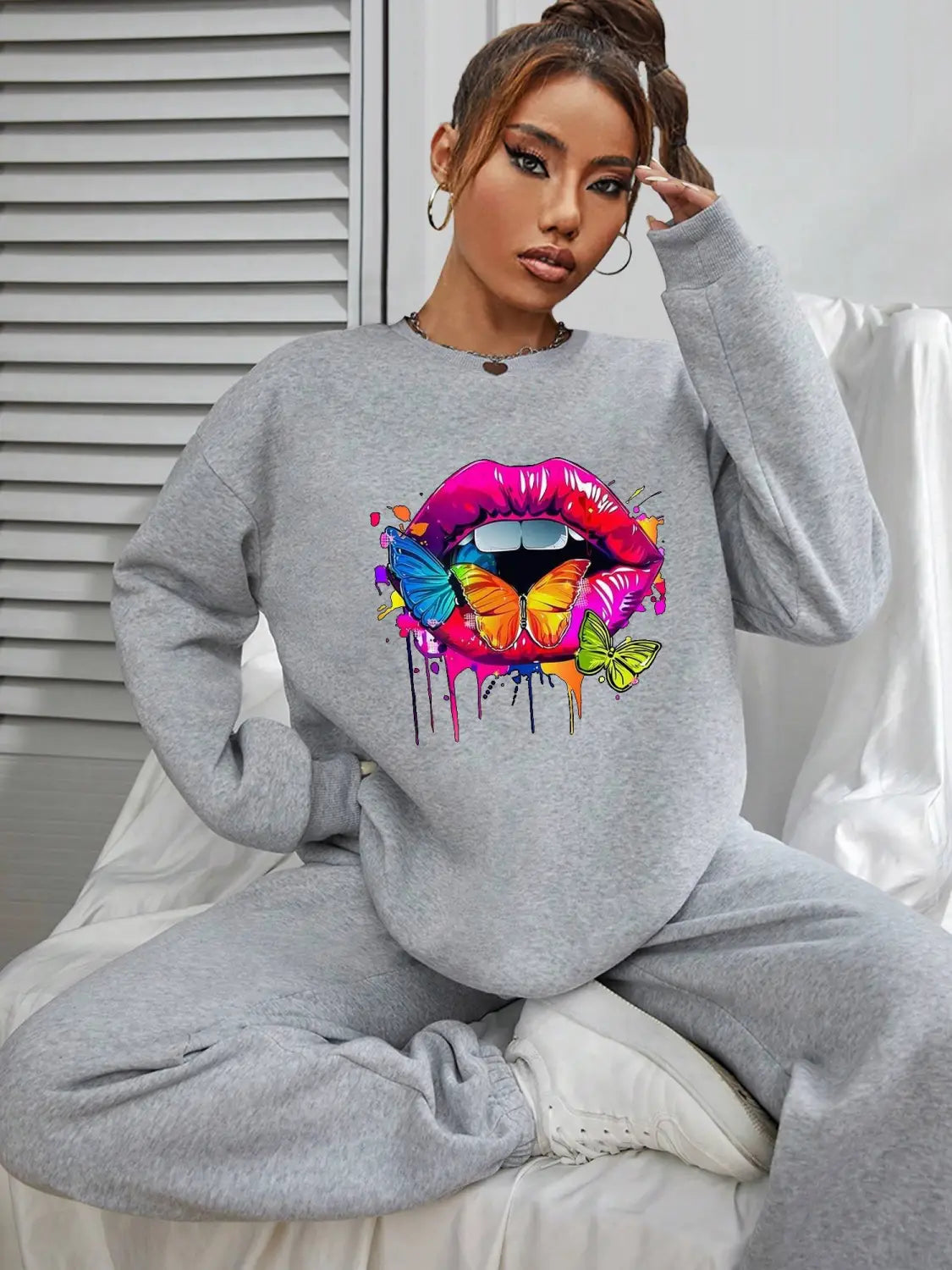 gray crew neck sweatshirt featuring a vibrant colorful graphic of lips and white butterflies on the front