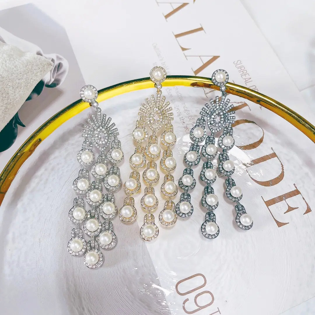 three elegant silver pearl micro inlay zircon style beaded fringe earrings with cascading strands of white pearls and sparkling rhinestones set in silver-toned metal featuring a sunburst design at the top