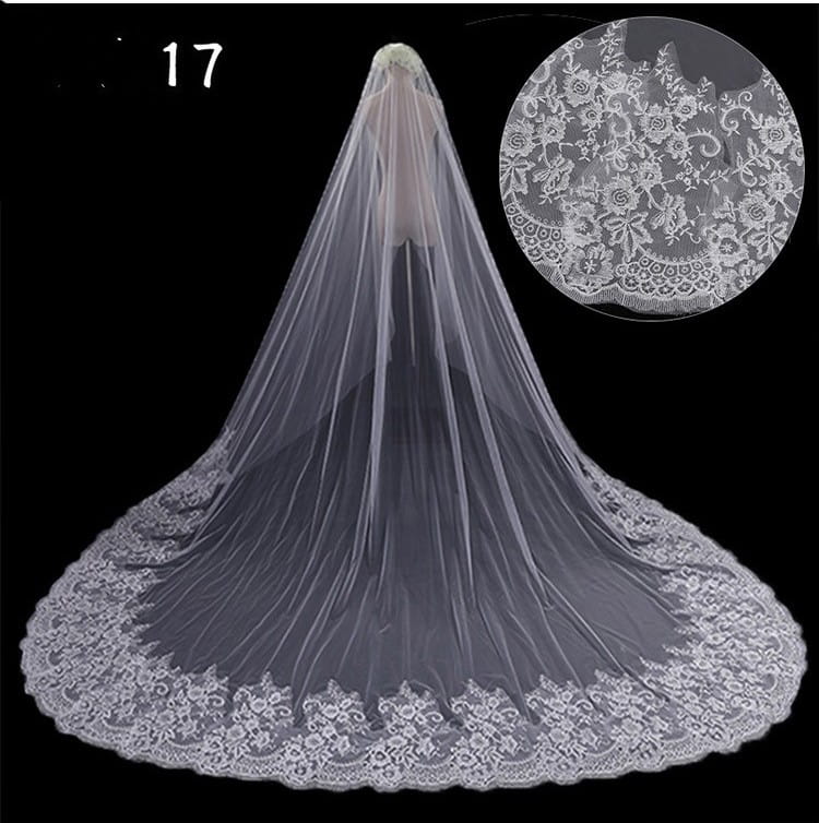 A delicate white lace wide style bridal wedding dress veil with an intricate floral pattern along its scalloped edge and a hair comb attachment.