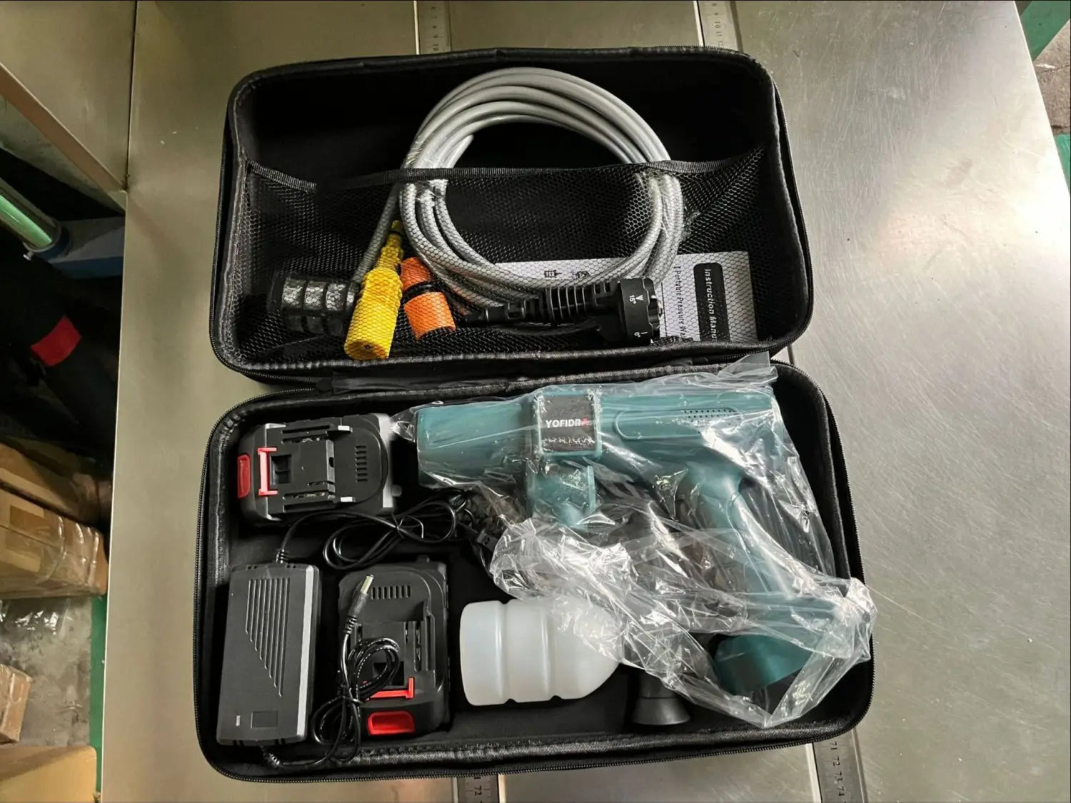 teal yogear cordless multifunctional car wash high pressure water gun with black battery and charger in a black carrying case.
