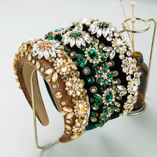 A decorative baroque vintage court style headband embellished with intricate floral designs featuring sparkling green and gold rhinestones.